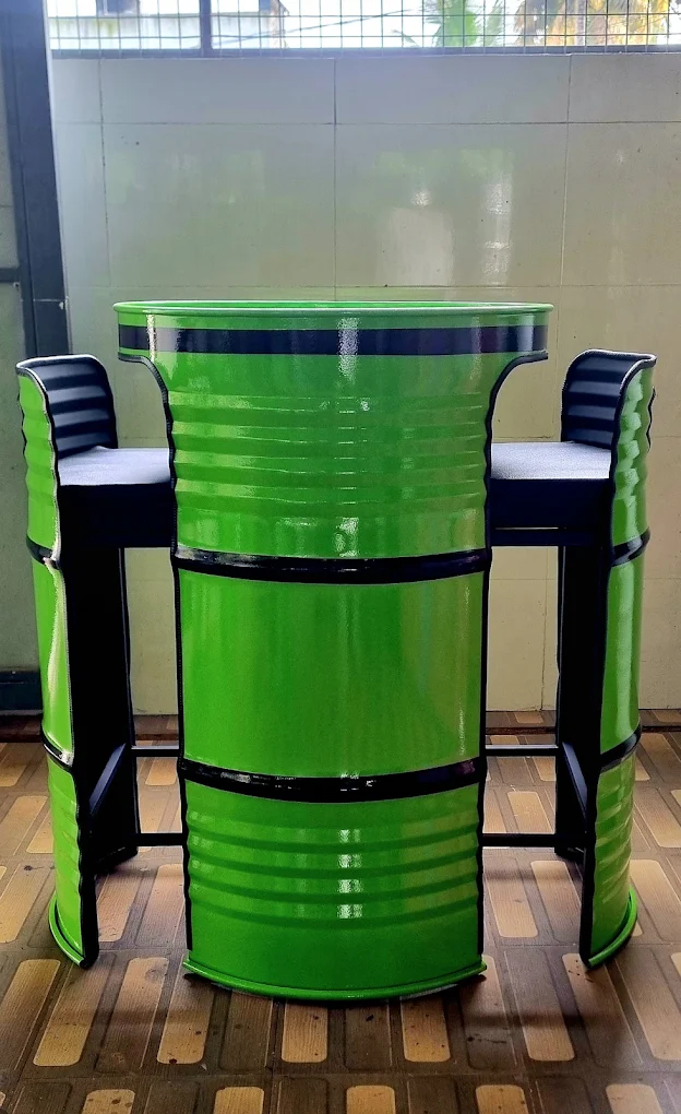 Bright green steel-barrel bar table flanked by two green cushioned drum bar stools